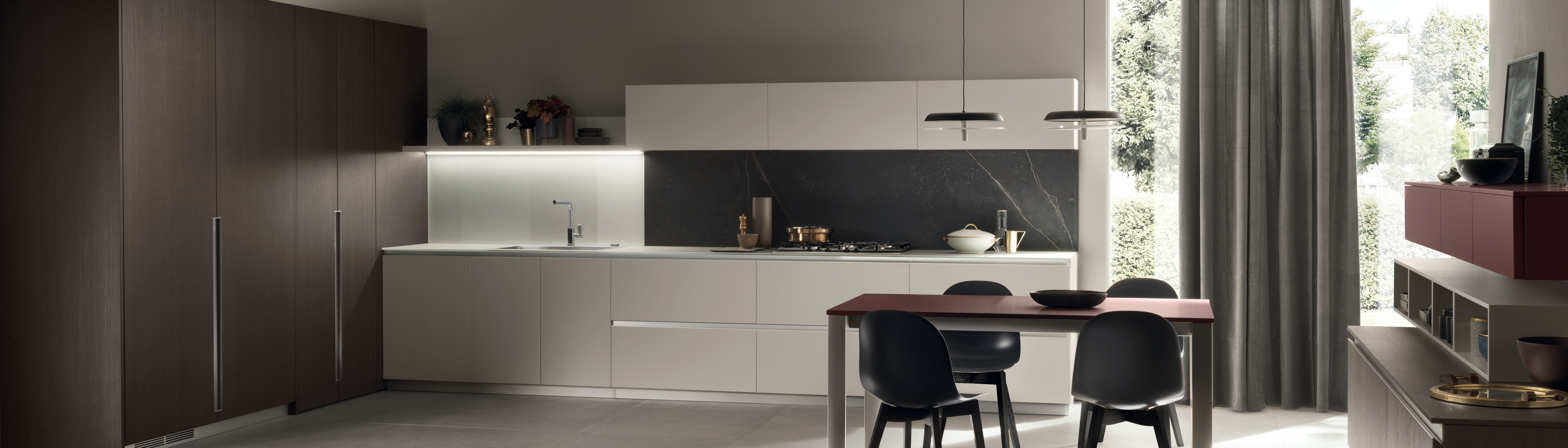 Modern kitchen with sleek cabinetry, a dining table, and large windows letting in natural light. Minimalist design and neutral tones.