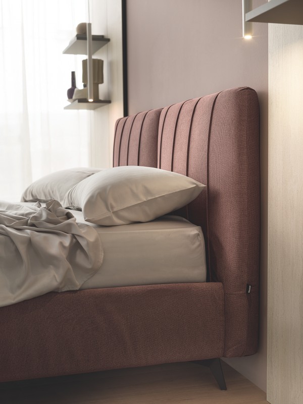 Olimpia系列配有柔软的床头板，该床头板采用特殊的填充料，并配有垂直绳缝轮廓。Delta支脚采用摩卡色饰面金属制成，高13.5cm。